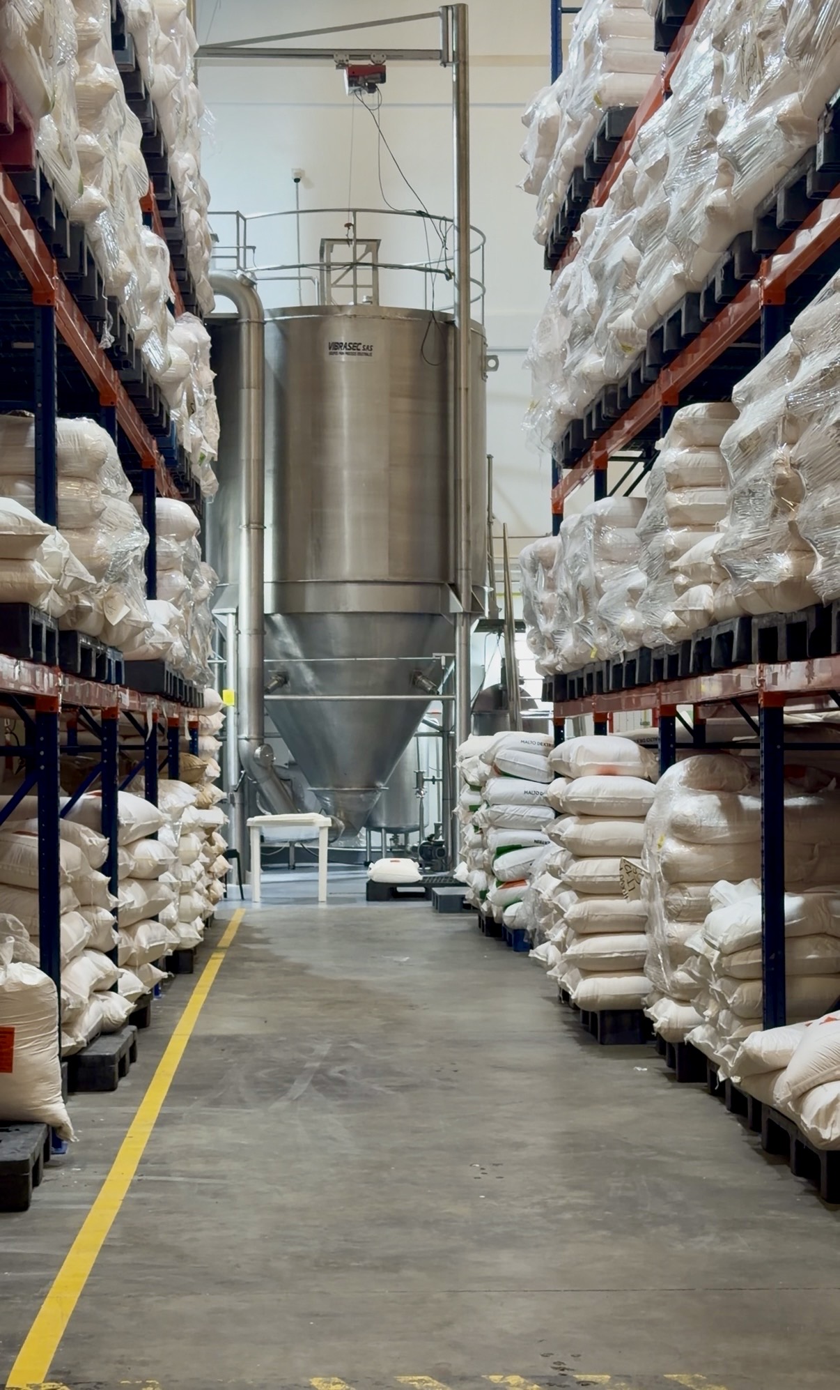 Técnico inspeccionando pallet con bolsas de kraft en bodega de ingredientes alimentarios